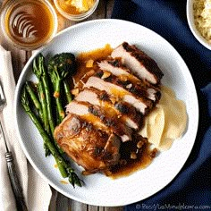 a white plate topped with meat and veggies next to bowls of gravy