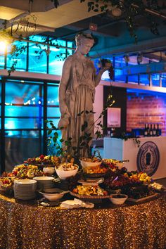 a statue is standing in front of a table full of plates and bowls with food on it