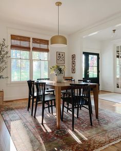 the dining room table is surrounded by black chairs and an area rug that matches the hardwood floor