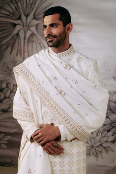 Ivory full sleeve sherwani with all over blooming flower embroidery in resham and zari work. Paired with an inner kurta and trouser. Comes along with embroidered stole.
Components: 4
Pattern: Embroidery
Type Of Work: Resham, Zari, Blooming Flower
Neckline: Stand Collar
Sleeve Type: Full Sleeves
Fabric: 100% Silk 
Color: Ivory
Other Details: 
Flower vine embroidered stole
Occasion: Groom,Wedding - Aza Fashions Wedding Sherwani With Floral Embroidery In Traditional Drape, Wedding Sherwani With Floral Embroidery And Traditional Drape, Wedding Sherwani With Floral Embroidery, Traditional Off White Sherwani With Intricate Embroidery, Traditional Off-white Sherwani With Intricate Embroidery, Cream Sherwani With Chikankari Embroidery And Long Sleeves, Cream Long Sleeve Sherwani With Chikankari Embroidery, Floral Embroidered Sherwani For Wedding And Festivals, Ceremonial White Dupatta With Naqshi Detail