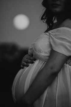 a pregnant woman wearing a white dress and holding her belly