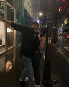 a man standing next to a woman on the side of a city street at night