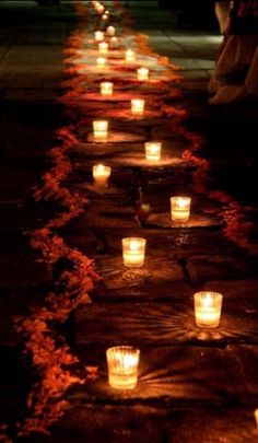 many lit candles are lined up on the ground