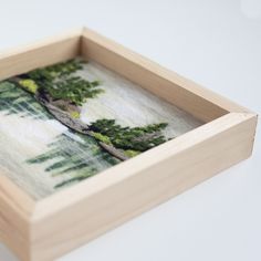 a small wooden box with an image of trees in the woods on it's side