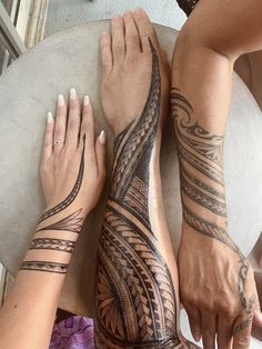 two people with tattoos on their arms and legs sitting next to each other in front of a table