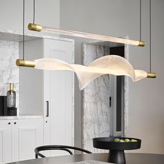 a modern kitchen with marble counter tops and white cabinets, along with brass fixtures on the ceiling