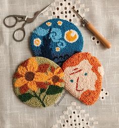 three crocheted coasters with flowers and scissors on a lace tablecloth next to them