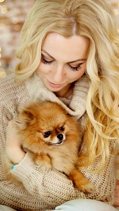 a woman holding a small brown dog in her arms and looking down at the camera