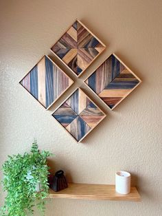 three wooden squares mounted on the wall above a shelf with a potted plant next to it