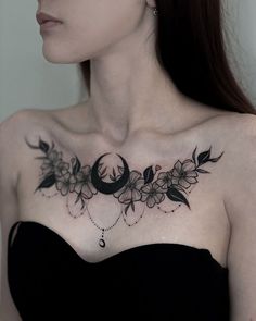 a woman wearing a black strapless dress with flowers on her chest and crescent moon tattoo