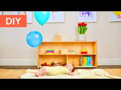 a baby is laying on the floor with some balloons in front of him and there are pictures above it