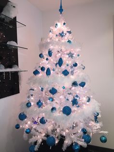 a white christmas tree with blue and silver ornaments