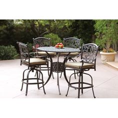 an outdoor table with four stools and fruit on the table in front of it