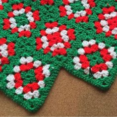 a green and red crocheted dishcloth with white flowers on it's edges