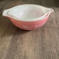 a pink and white bowl sitting on top of a wooden table