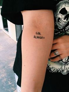 a woman with a skull tattoo on her arm and the word girl almutity written in black ink