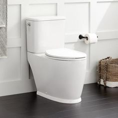 a white toilet sitting in a bathroom next to a towel dispenser on the wall