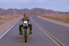 a man riding on the back of a motorcycle down a road