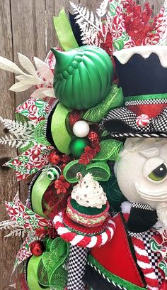 a close up of a christmas wreath on a wooden fence with an owl wearing a top hat