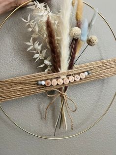 a person is holding a piece of wood and some feathers on a circular object with string