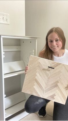 a girl is holding up a wooden object