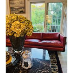 a living room filled with furniture and a large vase full of flowers on top of a table