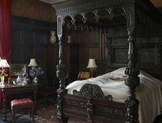 a bedroom with a four post bed and red curtains