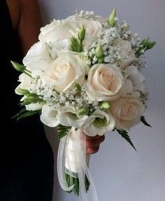 a bridal bouquet with white roses and baby's breath in someones hand