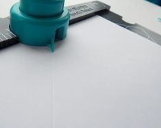 a blue rubber stamper sitting on top of a piece of paper next to a ruler