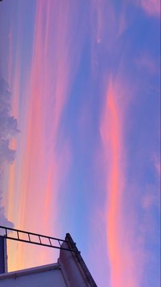 the sky is filled with colorful clouds and pinkish hues, as seen from an apartment building