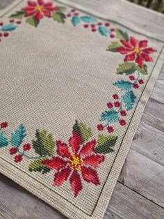 a close up of a table cloth on a wooden surface with flowers and leaves painted on it