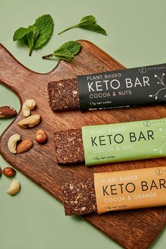 three bars of keto bar sitting on top of a cutting board next to nuts