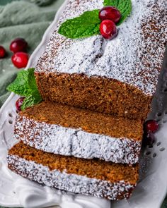 two slices of cake on a plate with powdered sugar and cranberries