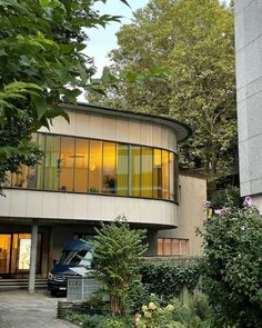 a car is parked in front of a modern house with trees and bushes around it