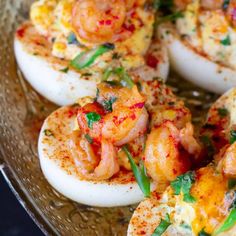 deviled eggs topped with shrimp and cheese on a glass platter, ready to be eaten