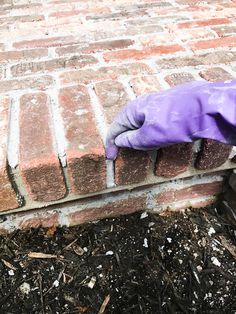 a purple glove sitting on top of a brick wall next to a pile of dirt