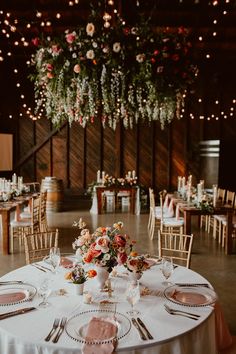 the tables are set up for a wedding reception with floral centerpieces and candles