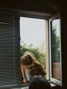 a woman is looking out the window with her head in the window sill,