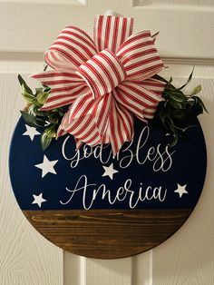 a patriotic door hanger that says, you're less america and has a bow on it