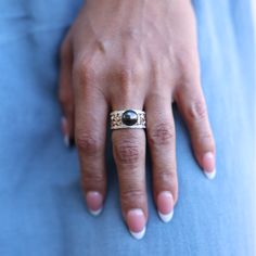 a close up of a person's hand with a ring on their finger, wearing blue pants