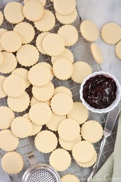 some cookies are on a cooling rack with a bowl of jam