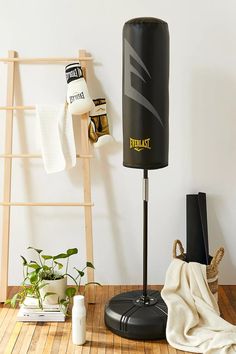 a black punching bag sitting on top of a wooden floor next to a white wall