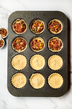 twelve mini pies in a muffin tin on a marble countertop with small bowls