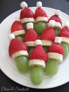 grapes and strawberries dressed as santa hats on a plate