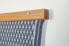 a blue and white blanket hanging from a wooden hook on a wall next to a wood frame