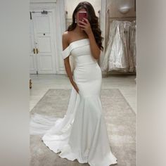 a woman in a white dress taking a selfie with her cell phone while standing on the floor