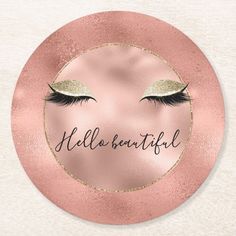 a round coaster with eyelashes and the words hello beautiful in gold glitter on top of it