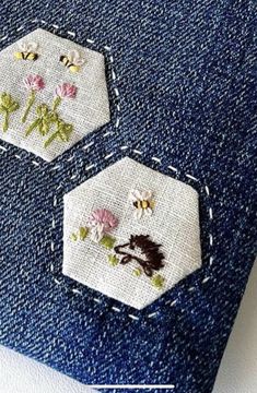 two pieces of fabric with embroidered flowers and bees on them, sitting next to each other