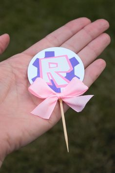 a hand holding a pink and purple lollipop with the letter p on it