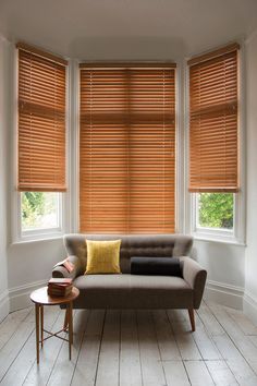 a couch sitting in front of two windows with wooden blinds on it's sides